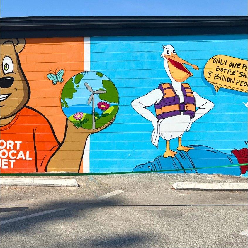 Painted outdoor mural of a pelican and bear on a cinder-block wall