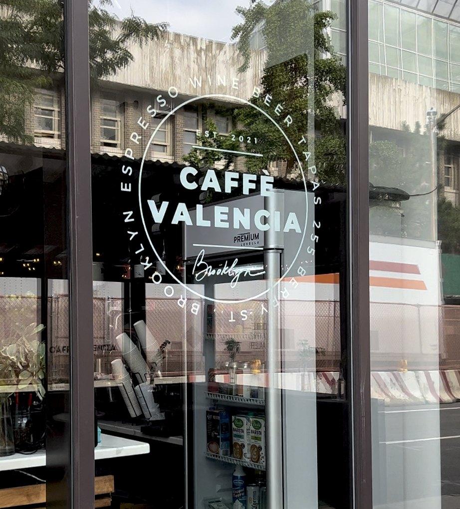Circular Caffè Valencia logo decal on a café glass door
