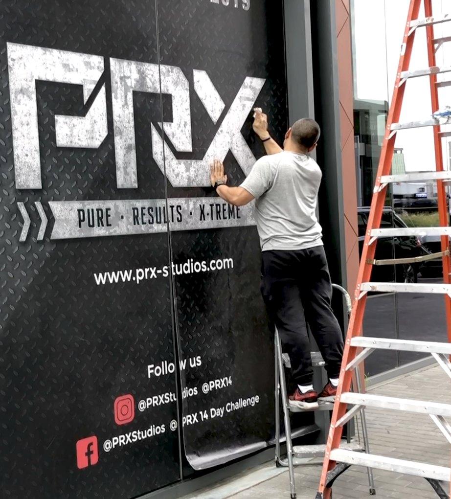Installer applying a large PRX gym storefront graphic