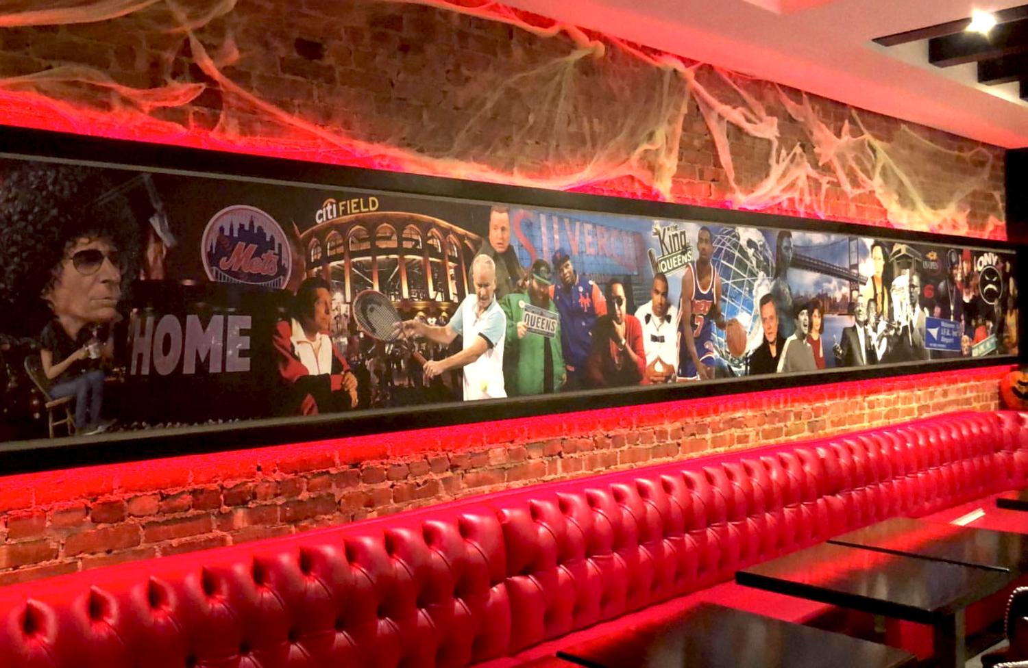 Long Queens tribute mural above red tufted booth seating