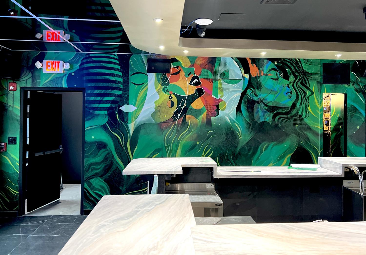 Green abstract faces mural behind the bar at Partake Lounge
