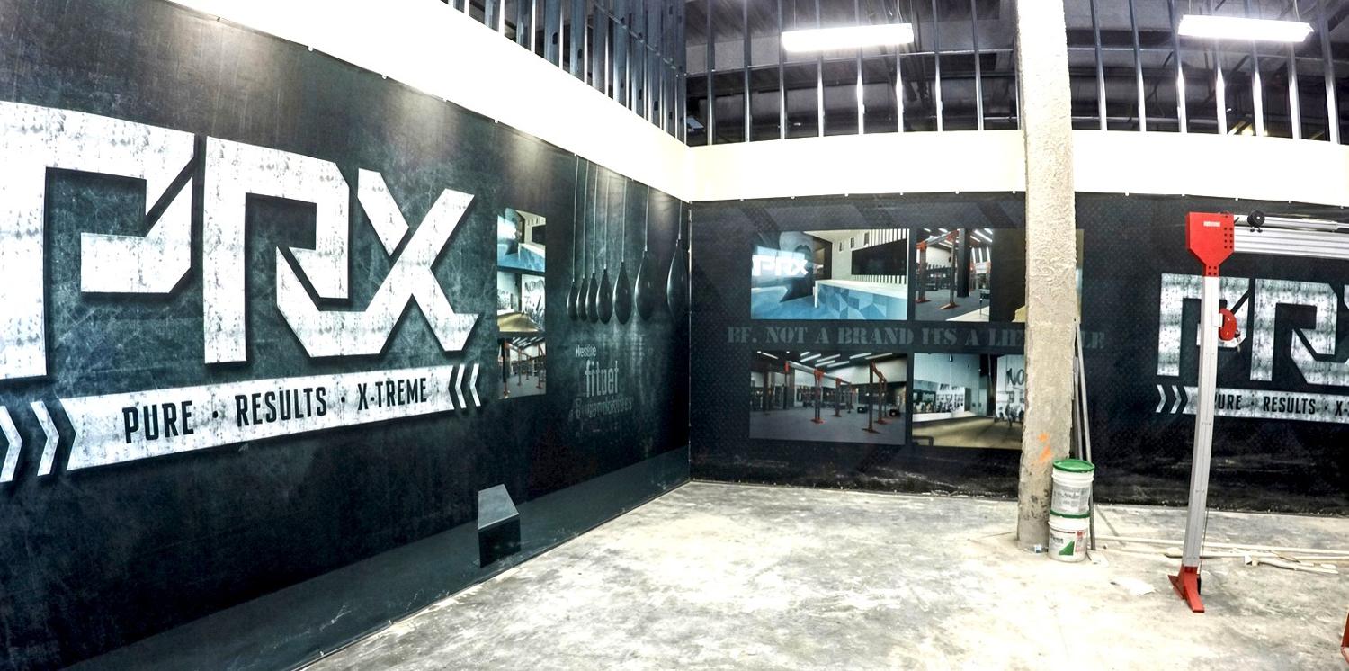 PRX gym walls wrapped in branded black graphics during build-out