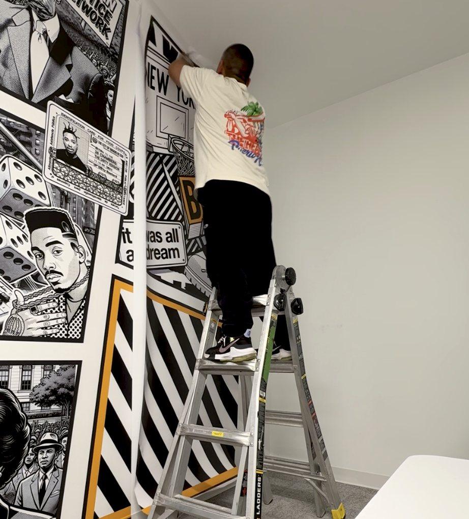 Installer hanging a black-and-white illustrated wallpaper