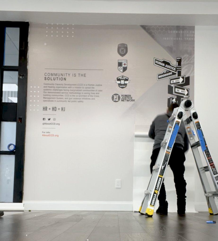 Installer finishing a branded lobby wall graphic